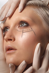 many hands wearing latex medical gloves holding beauty woman face, plastic surgery concept