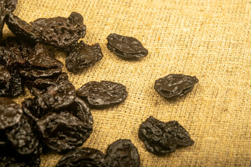 Dried prunes in bulk on burlap with a rough texture. Close up.