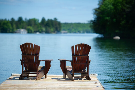 Two Adirondack chairs on a wooden dock overlooking a calm lake in Ontario cottage country. Retirement planning.