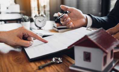 Home agents are explain to customers signing a contract to buy a new home.