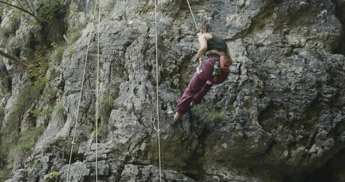 Female paralympic climber woman athlete with missing fingers on left hand descend rappel after rock climb outdoors lifestyle sport in nature
