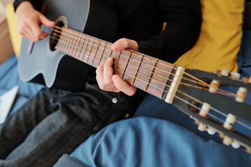 Fototapeta na wymiar Close-up image of teenager playing guitar and singing song at home