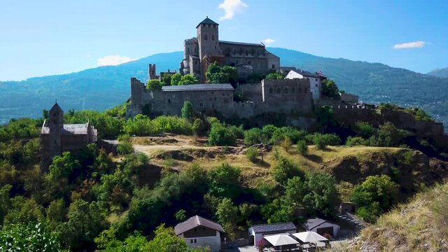 Static shot of epic medieval Swiss castle on hill in Alps on sunny summer day