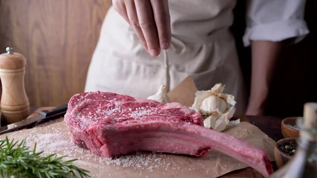 chef seasoning tomahawk steak meat with salt