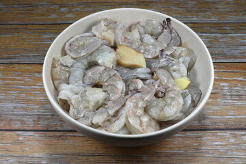 Fresh peeled shrimp marinated with sliced ginger in the bowl. Preparation food in Thai kitchen. Famous uncooked ingredients seafood in Asia. 