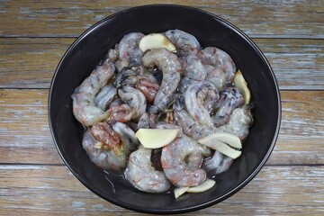 Fresh peeled shrimp marinated with sliced ginger in the bowl. Preparation food in Thai kitchen. Famous uncooked ingredients seafood in Asia. 