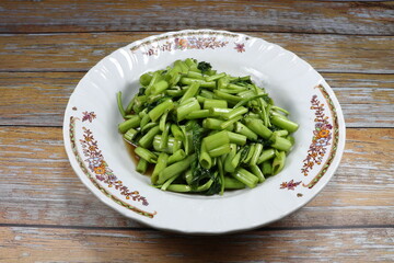 Fried cutting fresh morning glory seasoning with soy sauce and pepper on the plate. Famous stirred...