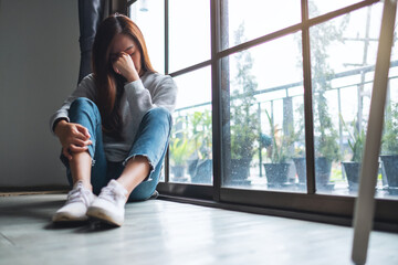 A sad and stressed young asian woman sitting alone in the room