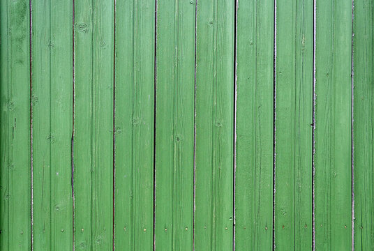 Vertical wooden lining background. Green colored wooden texture. Old wooden boards on house wall. Close-up. Striped background of vertical narrow wooden boards painted green.