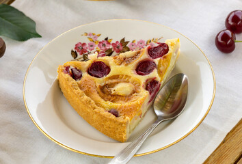 Piece of fruit cake with sour cream filling, apricots and cherries on a white plate