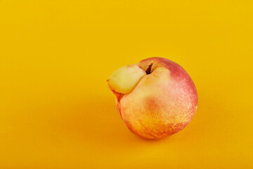 An ugly fruit or vegetable. Very ugly peach mutant on an orange background. Ugly fruits are not in...