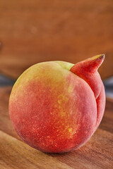 ugly fruit or vegetable. Heavily ugly peach mutant on a wooden background. Ugly fruits are not in high demand