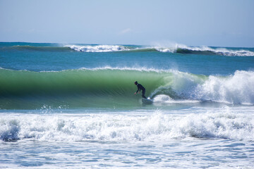 Japan surfing , sometimes during a typhoon, there are many waves in Japan especially in Hebara, Katsuura, Chiba. Westerner surfs large waves. Sunrise & at the beach with a surfer & his surf board.