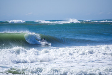Japan surfing , sometimes during a typhoon, there are many waves in Japan especially in Hebara, Katsuura, Chiba. Westerner surfs large waves. Sunrise & at the beach with a surfer & his surf board.