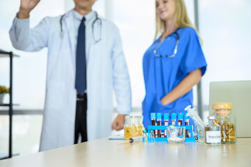 Fototapeta premium Lab equipment with liquid inside stand on the table with doctors wearing formal white coat and blue scrubs suit at the background.