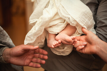 The baptism of a child. The godfather holds the child in his arms. Closeup photo, priest and...