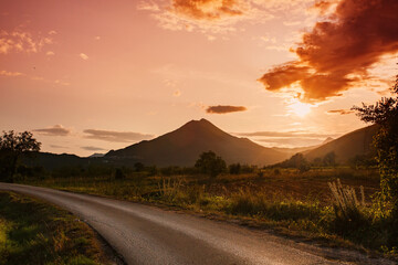 Amazing mountain landscape with vibrant sunset and country road
