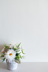 Fototapeta na wymiar Wall mockup with pot of flowers on white surface. Copy space.