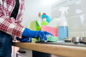 young woman cleaning in rubber gloves and sponge in the kitchen at home