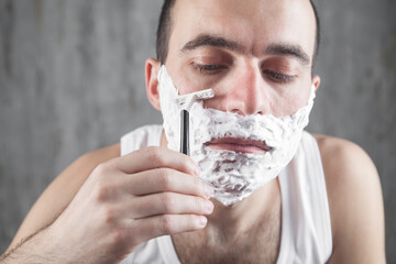Caucasian man shaving in home.
