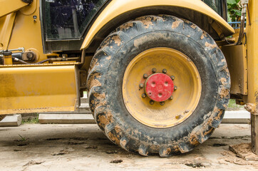 Fototapeta na wymiar Big black tire of yellow tractor close up