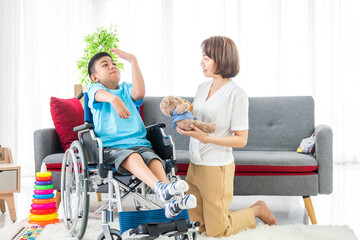 asian woman playing with disabled child on wheelchair in living room