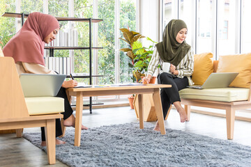 asian muslim women wear hijab talking about business with laptop in office.