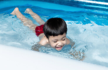 Fototapeta na wymiar Little boy play in home water pool on garden summer day.
