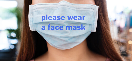 Close up of young Asian woman wearing protective face mask writing please wear a face mask....