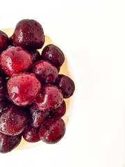 Bright juicy red cherry on a white background in drops of water.