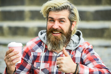 best ever. Handsome calm bearded man outdoors with a cup of coffee. drinking hot coffee. tourist relaxing on stairs drink tea or coffee. Coffee on the go. man with a cup outdoors