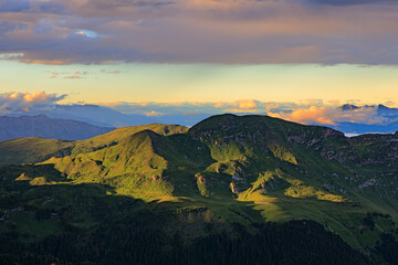 La luce dell'alba illumina il verde delle montagne