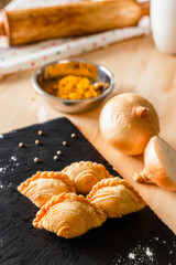 Curry puff on a dark plate and ingredients