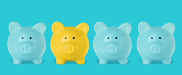 Yellow piggy bank among blue ones on color background