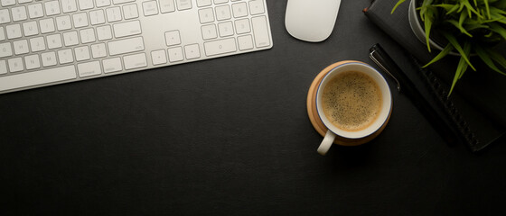 Dark office table with copy space, coffee cup, computer device and decoration