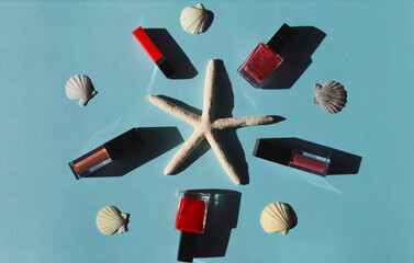 Summer composition with starfishes, shells and makeup set on blue background with sun light.