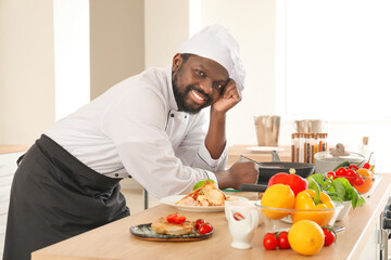 Male African-American chef with tasty dish in kitchen
