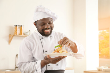 Male African-American chef with tasty dish in kitchen