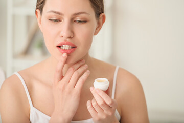 Beautiful young woman with lip balm at home