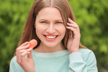 Beautiful young woman with lip balm outdoors