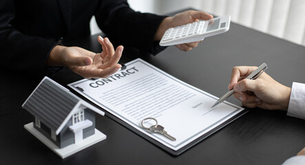 Female salesman is negotiating a home transaction with a male client in the office.