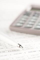 Pocket calculator with pen on financial analysis sheet background - tax, finance or accounting concept