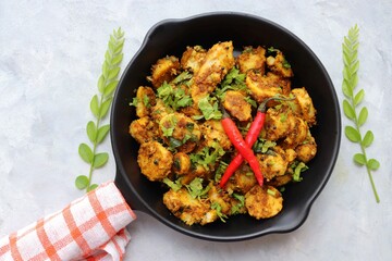 Stir fried taro roots. Arbi ki sabji, Taro roots masala curry. Arbi Masala. Garnished with coriander, red chili & curry leaves. copy space.