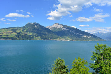 Fototapeta na wymiar Magnificent view of lake Thun and the Alps, Switzerland. Blue sky, blue water, boats, green trees. Sunny summer weather.