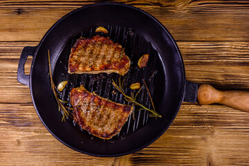 Roasted steaks with garlic, rosemary and spices in a cast iron grill pan. Top view