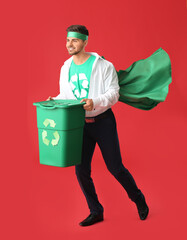 Man dressed as eco superhero with trash bin on color background