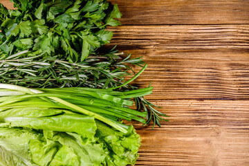 Lettuce rosemary and parsley on a wooden table. Vegan food. Top view