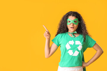 Woman dressed as eco superhero showing something on color background