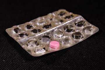 Last antibiotic pill in blister pack on a black background. Healthcare and medicine concept