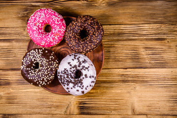 Plate with glazed donuts on a wooden table. Top view